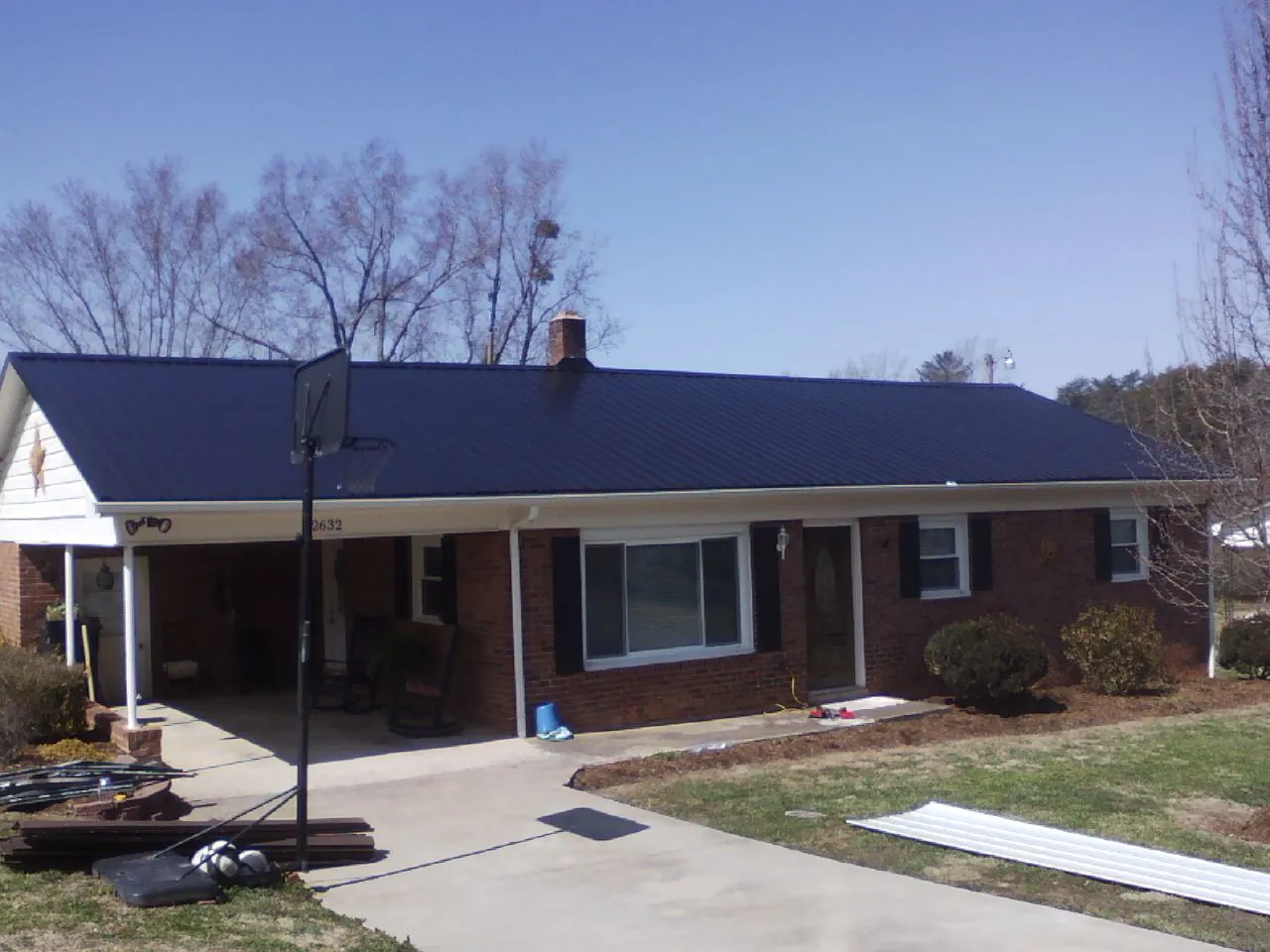 Finished dark blue metal roof on a brick ranch with a carport in Geneva